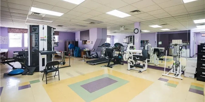 A gym room with exercise equipment and a purple wall.