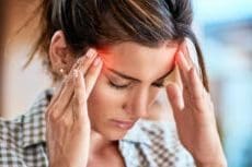 A woman is holding her head in pain, possibly indicating a migraine.