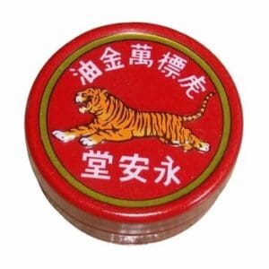 A red tin with a Tiger Balm Pain Relieving Ointment - Red Extra Strength - Small on it.