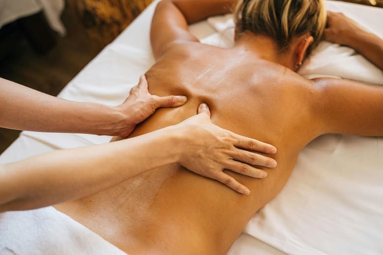 A woman receiving a back massage in a spa.