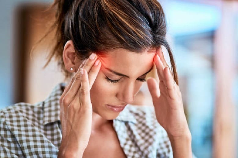 A woman holding her head with her hands, contemplating acupuncture.