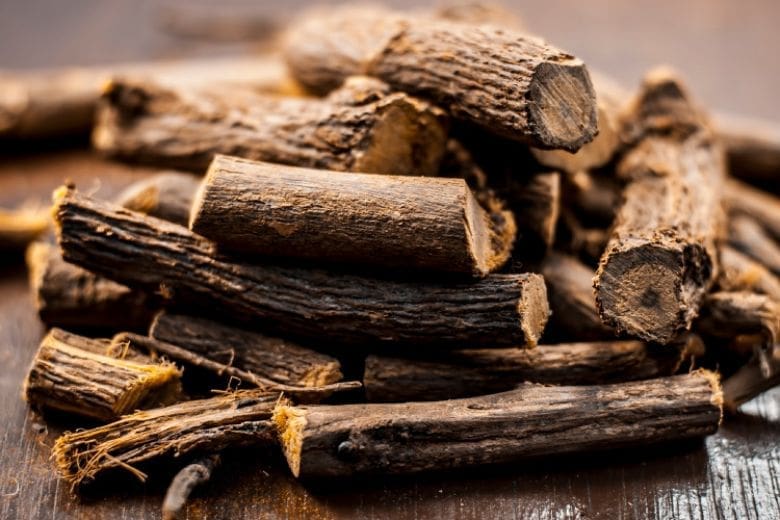 A pile of dry licorice roots on a wooden surface.