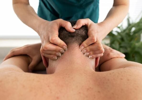 A person is receiving a head massage while lying on their stomach. The masseuse's hands are placed on the person's head.