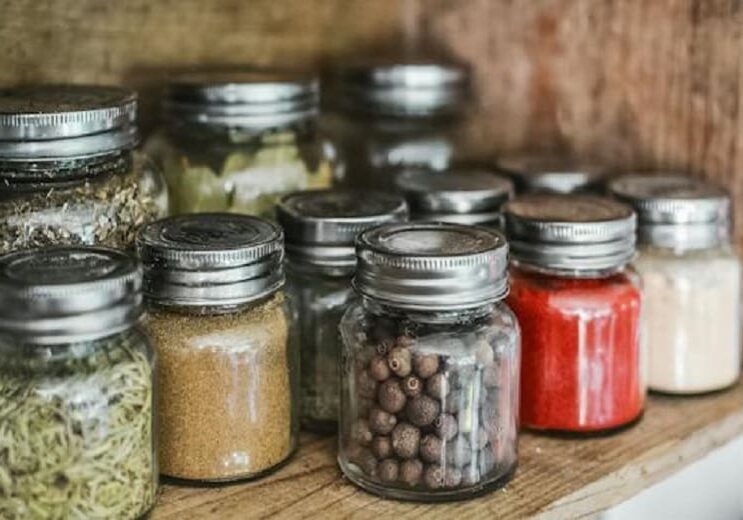 Spice jars on a wooden shelf.