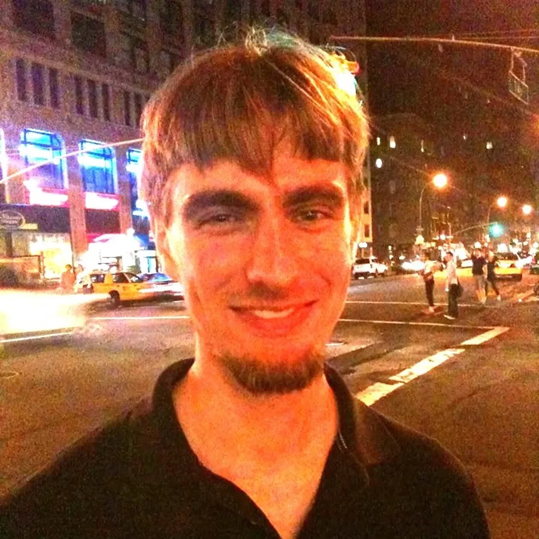 A man in a black shirt standing on a street at night.